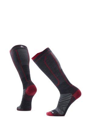 Par de calcetines deportivos hasta la rodilla, negros y rojos, con patrones geométricos y zonas reforzadas en el talón y la puntera.