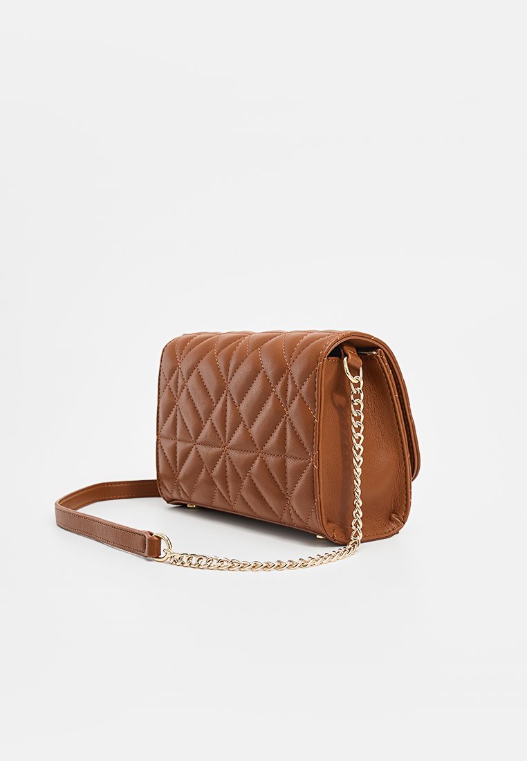 Sac en bandoulière en cuir marron matelassé avec une chaîne en or et un coussinet en cuir sur fond blanc.