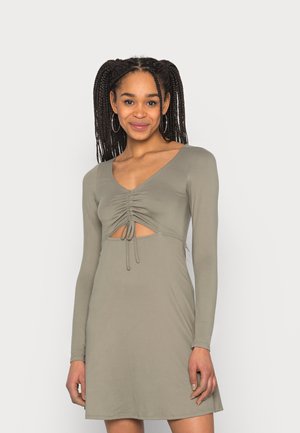 Vestido de manga longa, verde oliva, com decote em V, detalhe franzido no busto e recorte na cintura com laços ajustáveis. Textura suave.