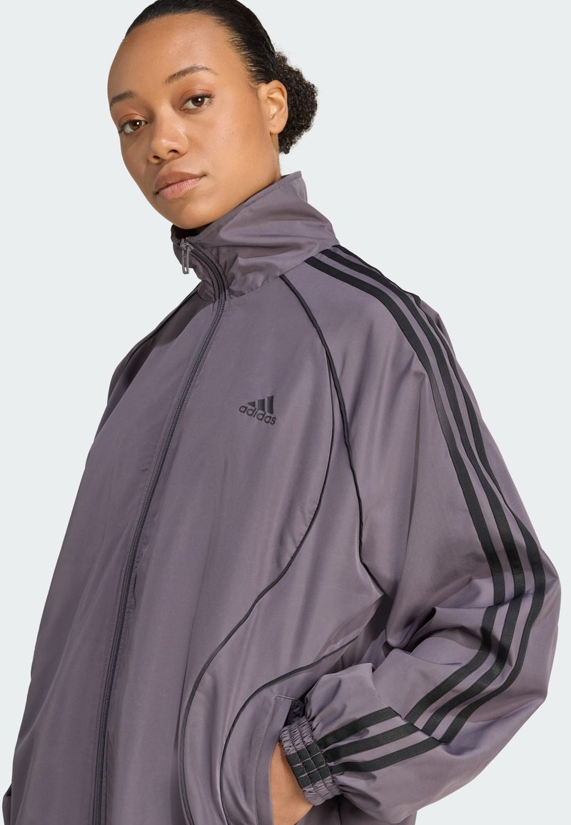Lightweight, mauve athletic jacket with a high collar, zip closure, and black three-stripe design along sleeves. Elasticized cuffs.
