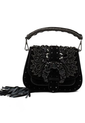 Bolso de terciopelo negro con adornos de joyas, tachuelas metálicas, asa trenzada y acentos con flecos. Forma rectangular compacta.