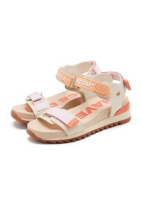 Sandalias ligeras con un empeine beige y acentos en rosa y naranja, correas ajustables, suela texturizada y texto en negrita en la plantilla.