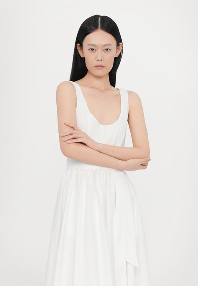 Weißes ärmelloses Kleid mit Rundhalsausschnitt, tailliertem Bund und fließendem Rock. Glatte Textur mit einem Banddetail in der Taille. Minimalistisches Design.