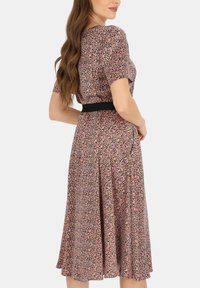Sukienka w kwiatowy wzór w różowo-czarnych odcieniach, z krótkimi rękawami, z talią podkreśloną czarnym paskiem oraz lekko skrojoną spódnicą z plisowanym wzorem.