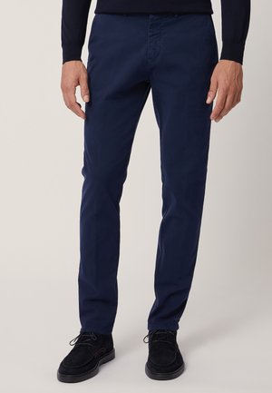 Pantaloni chinos in cotone blu navy con una vestibilità slim, caratterizzati da una texture liscia, tasche anteriori e una vita con passanti per cintura.