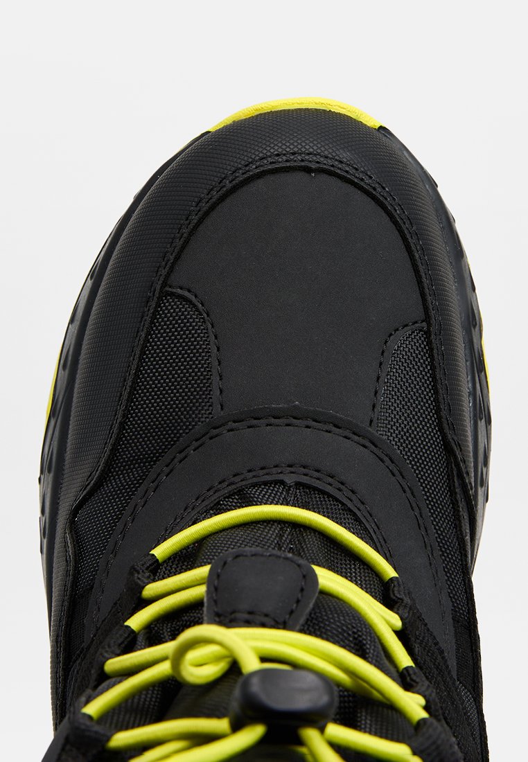 Schwarze Sneaker mit strukturiertem Obermaterial, gelben Schnürsenkeln und einer gepolsterten Zunge mit runder Form und leicht erhöhter Sohle.