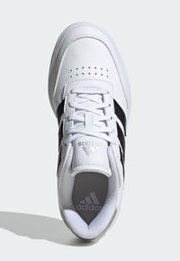 White athletic shoe with black stripes, made of leather, featuring a rounded toe, lace-up front, and perforated detailing on top.