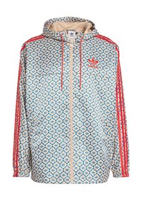 Chaqueta ligera con capucha en color crema con un patrón floral azul, acentos rojos y tres rayas rojas en las mangas; cuenta con un cierre frontal y bolsillos laterales.