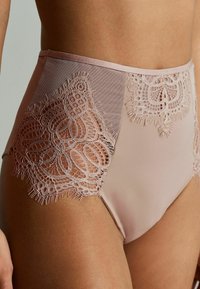 Hochtaillierte, hellrosa Lingerie aus durchsichtigem Netz mit filigranen Spitzenverzierungen an den Seiten, mit gewellten Kanten und strukturiertem Design.