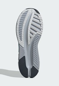 Semelle de chaussure de course en gris et noir, avec du caoutchouc texturé pour l'adhérence, des rainures dynamiques pour la flexibilité et un talon renforcé pour le soutien.