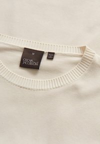 Beige trui met een geribde halslijn, zachte textuur en een label met de tekst "Oscar Jacobson, Made in Italy." Maatlabel: M.