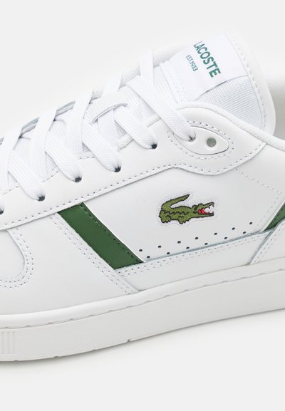 Бяла маратонка Lacoste със зелени детайли, бели връзки и бродирано лого на крокодил на кожена странична панел.
