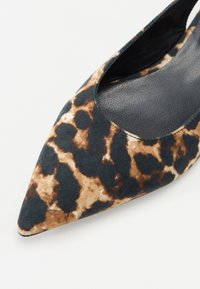 Zapato plano de punta fina que presenta un patrón de estampado animal multicolor en tonalidades de marrón y negro, con una parte superior de tela suave y un interior texturizado.