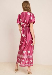 Roze satijnen maxi-jurk met pofmouwen, elastische taille, bloempatroon en randdetails. Zachte textuur, lengte tot halverwege de kuit.