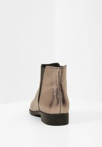 Metallinhohtoiset nilkkurit, joissa on sileä nahkapinta, joustavat sivupaneelit ja matala, tasainen korko. Yksinkertainen muotoilu, jossa minimaalinen korostus.