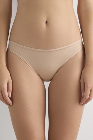 Beige naadloze slips met een middelhoge taille, voorzien van een gladde textuur en subtiele stikdetails langs de elastische tailleband.