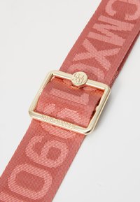 Pink woven fabric belt with embossed pattern, featuring a gold rectangular buckle and engraved logo detail. Smooth texture and sturdy construction.