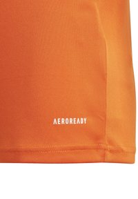 Camiseta atlética naranja con textura suave, que presenta un logo blanco de "AEROREADY" en la parte inferior. Diseño simple y funcional.
