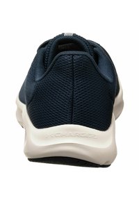 Marineblå sportsko med en struktureret netoverdel, fleksibel hvid sål og branding bagpå; designet til komfort og åndbarhed.