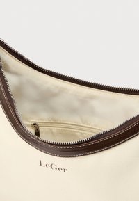 Κρεμ πανί τσάντα με καφέ δερμάτινη επένδυση και φερμουάρ, που δείχνει ανοιχτό εσωτερικό με μικρή τσέπη με φερμουάρ και λογότυπο "LeGer" μπροστά.