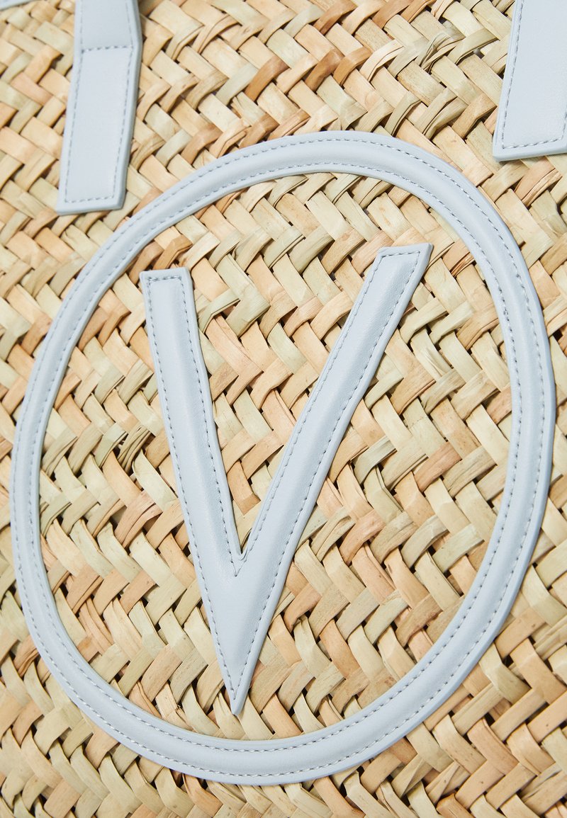 Sac en paille tissé avec un grand logo en cuir gris clair en forme de "V" et des textures tissées contrastantes beige et jaune.