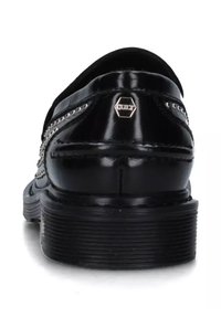 Scarpe in pelle nera con punta arrotondata, cuciture decorative e suola testurizzata. Accento metallico notevole vicino al tallone.