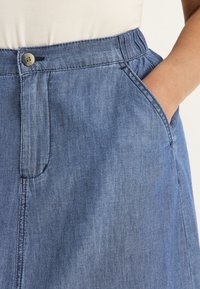 Jeanskjol i medelblått, med knappstängning, elastisk midja, sidofickor och en slät, texturerad yta.