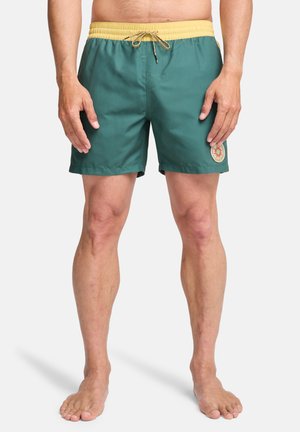 Męskie spodenki kąpielowe w zielonym kolorze z żółtym sznurkiem do wiązania. Gładki materiał, długość do połowy uda, z ozdobną naszywką z boku.