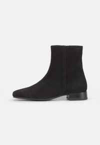Bottines en suède noir avec un bout pointu et un petit talon bloc. Texture lisse, couture minimale et détail de fermeture éclair sur le côté.