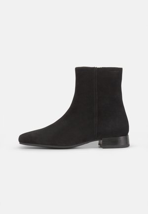 Botines de ante negros hasta el tobillo con punta afilada y un tacón bajo cuadrado. Textura suave, costuras mínimas y un detalle de cremallera lateral.