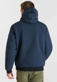 Giubbotto imbottito blu navy con colletto alto e cappuccio, dotato di polsini elasticizzati e fascia in vita, realizzato in tessuto liscio e resistente all'acqua.