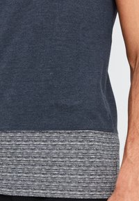 Mørkeblå t-shirt med en stribet kant i hvid og mørkeblå. Fremstillet af blødt stof med en afslappet pasform og korte ærmer.