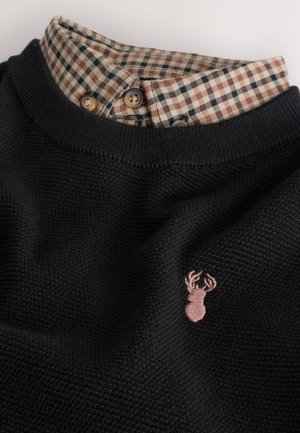 Črni pulover z teksturo in okroglim izrezom ter karo ovratnikom v bež in rjavi barvi, z majhno rožnato glavo jelena kot logotipom spredaj.