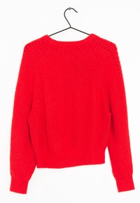 Roter Strickpullover mit gerippter Textur, Rundhalsausschnitt und Raglanärmeln; verfügt über offene Nähte an den Schultern. Hängt an einem schwarzen Haken.