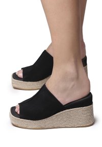 Zoccoli wedge aperti neri realizzati in un materiale scamosciato testurizzato con una piattaforma avvolta in juta, caratterizzati da un design elegante e minimalista.