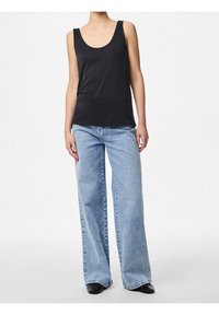 Top sin mangas negro combinado con jeans de pierna ancha de color azul claro y zapatos negros, mostrando un atuendo simple y casual.