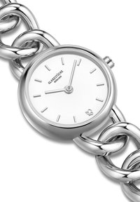 Sudraba pulkstenis ar baltu ciparu, saistīta ķēdes aproce, minimalistiskais dizains un stundu rādītāji. Iekļauta logo sešos pulksteņa stundās.