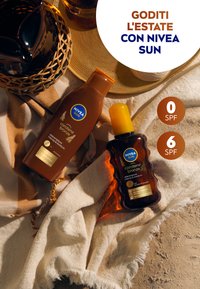 Due prodotti NIVEA Sun: una bottiglia marrone con un tappo arancione etichettata "carotene bronze" e una bottiglia spray di ambra scura, entrambi su un tessuto texture.
