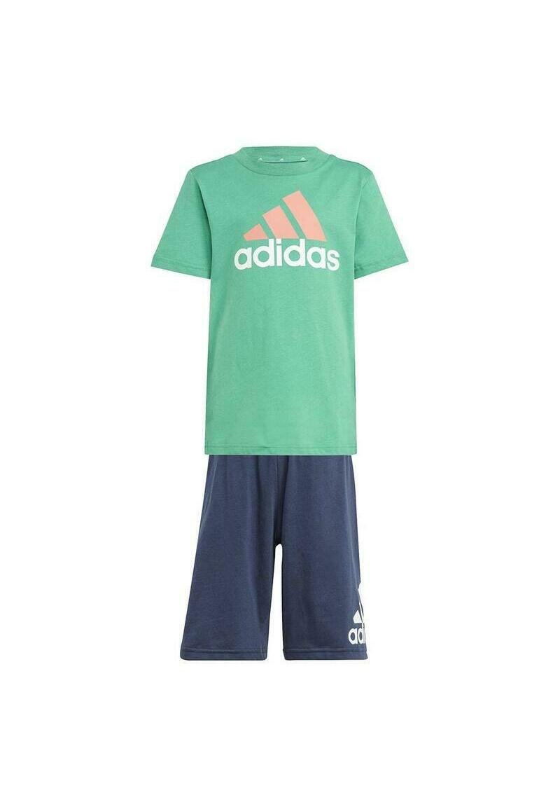 Maglietta verde in cotone con logo Adidas bianco e corallo, abbinata a pantaloni corti blu navy con un emblema Adidas bianco sulla gamba.