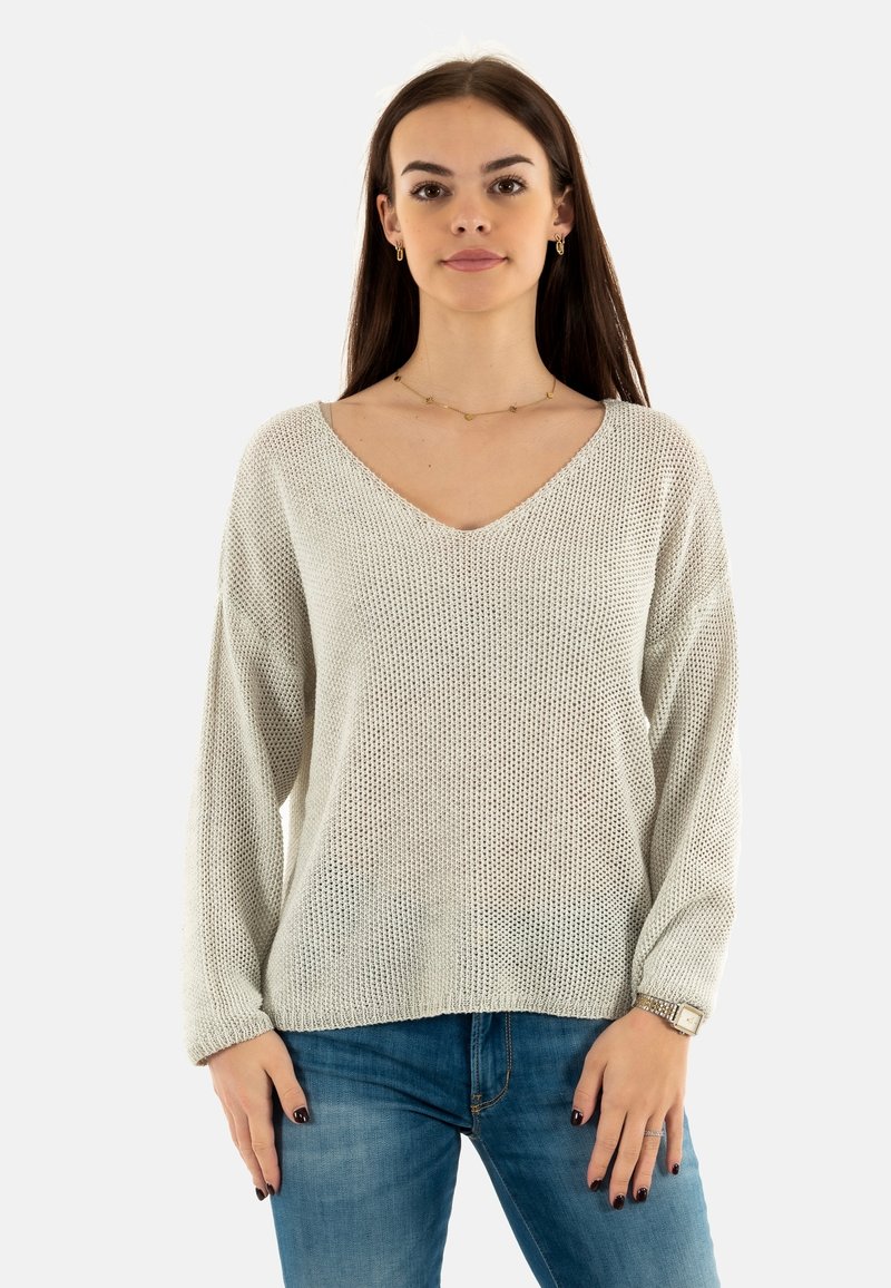 Jersey de punto gris claro con cuello en V y mangas holgadas, que presenta un patrón texturizado y un corte relajado, combinado con vaqueros azules.