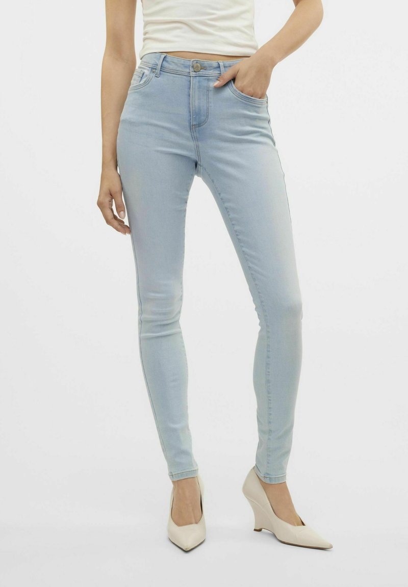 Jeans ajustados de color azul claro en denim elástico con una cintura de altura media, costuras mínimas, dos bolsillos frontales y un cierre de un solo botón.