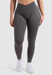 Hoch-taillierte, figurbetonte graue Leggings aus strukturiertem, dehnbarem Material, mit einem überkreuzten Bund und nahtlosem Design.