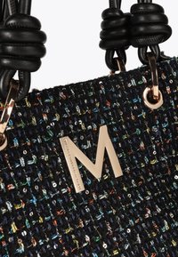 Černá kabelka z tweedového materiálu se třpytivými multikolorovými nitěmi, zlatými kovovými detaily a výrazným kovovým logem "M" na přední straně. Texturovaný povrch.