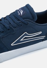 Σκούρο μπλε παπούτσια skate από καμβά και σουέντ, με λευκές ραφές, λογότυπο και υφασμένο λευκό καουτσούκ σόλα.