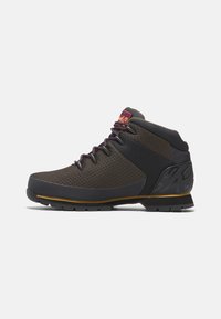 Scarpe da trekking marroni con parte superiore in rete, dettagli neri, suola in gomma e lacci viola. Design alto che offre supporto alla caviglia.