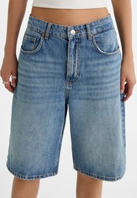 Lichtblauwe denim shorts met een relaxte pasvorm, vijf zakken, zichtbare stiksels en een middelhoge taille. Voorzien van een knoopsluiting en omgeslagen zoom.