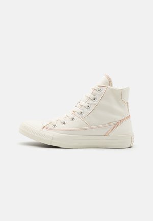 Off-white-värinen canvas-korkeavartinen lenkkari, jossa on kerma kumipohja ja reiät, korostetut ompeleet ja klassinen nauhakiinnitys.