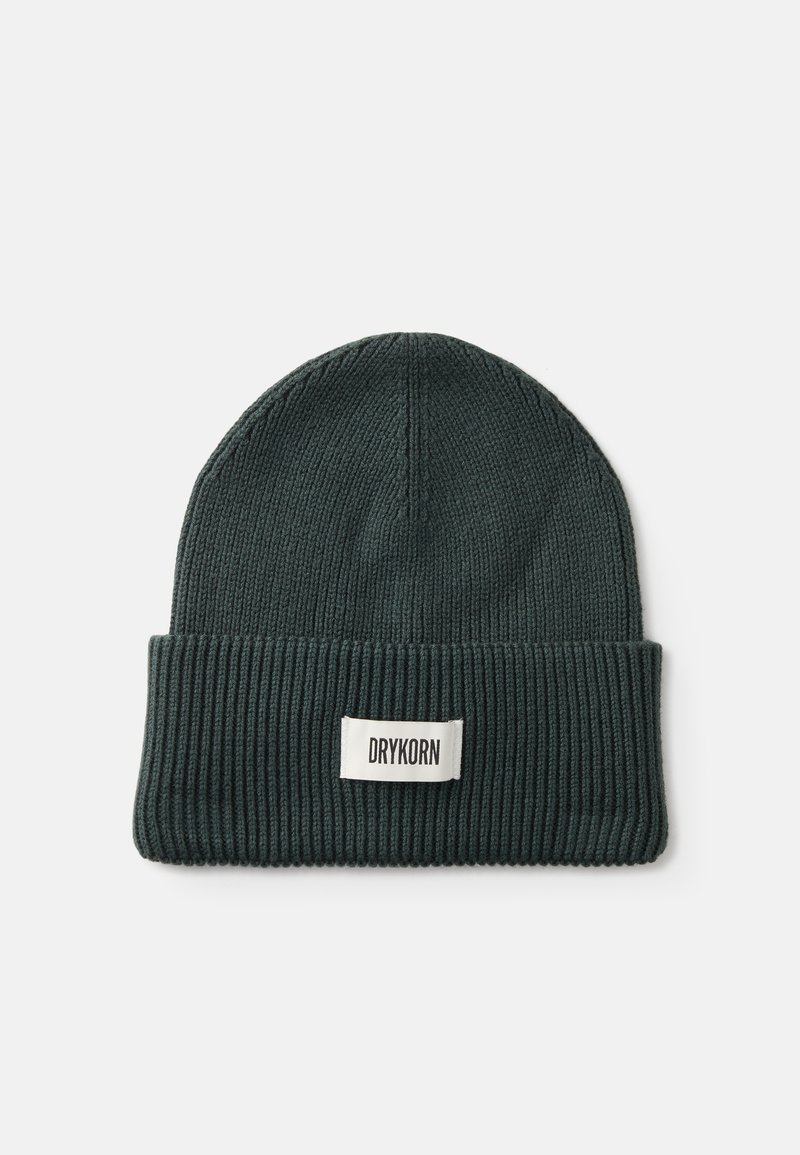 Pletená čepice v tmavě zelené barvě s žebrovanou strukturou a ohrnutým lemem, na kterém je obdélníková nálepka s nápisem "DRYKORN" v bílé barvě.