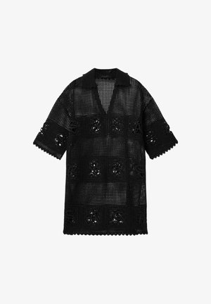 Robe en tricot crochet noir à manches courtes, col et bords festonnés, avec des carrés ajourés en motif formant le mot « SAS ».