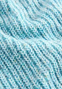 Tessuto lavorato a maglia in tonalità di azzurro chiaro con texture variabili. Il motivo presenta un design a coste, mettendo in mostra filati morbidi e pelosi.
